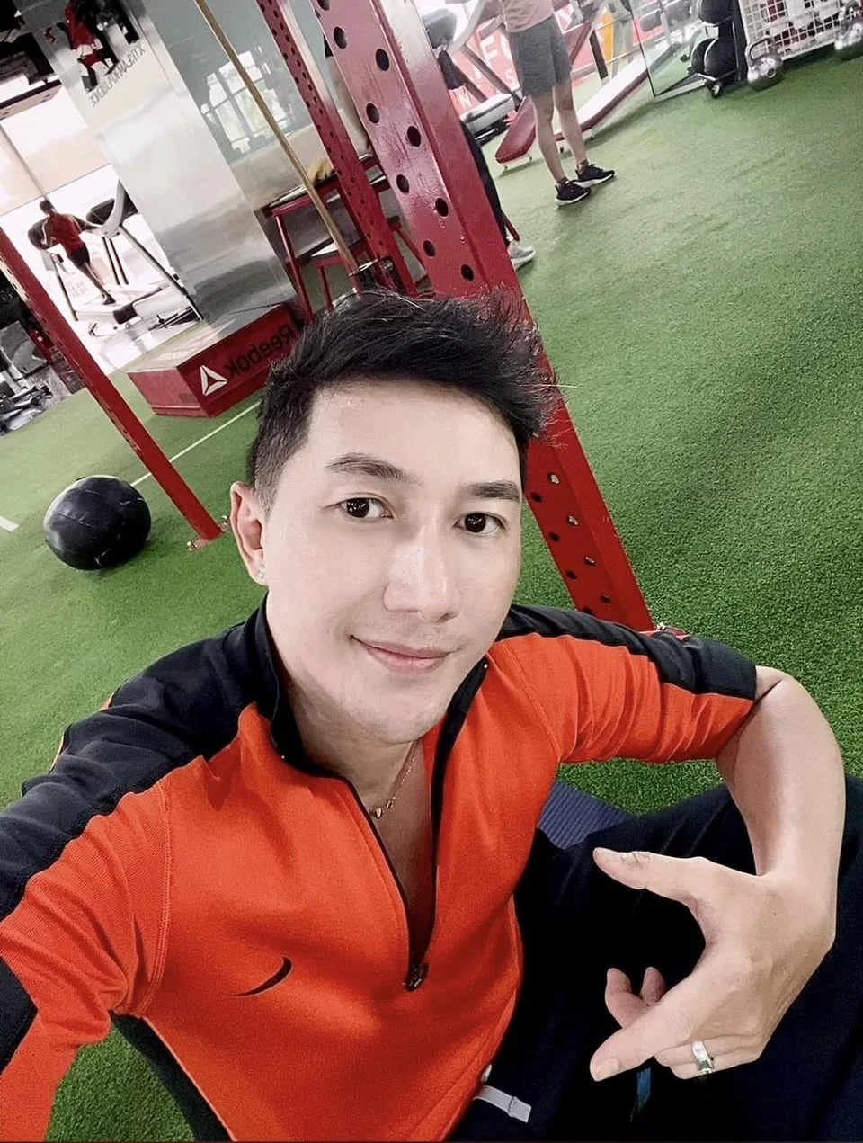 Người mẫu nam Phong selfie tại phòng gym mặc áo thể thao cam đen