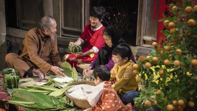 Gia đình quây quần gói bánh chưng bên cây quất trong ngày Tết