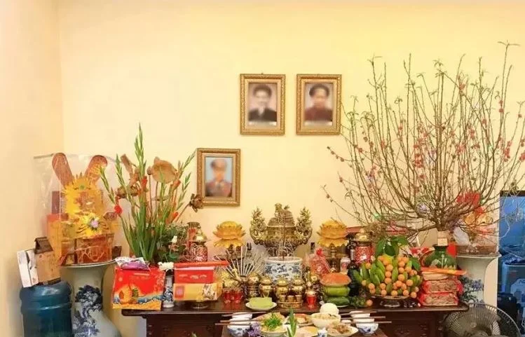 Bàn thờ gia tiên có treo ảnh người mất được trang trí hoa đào ngày Tết