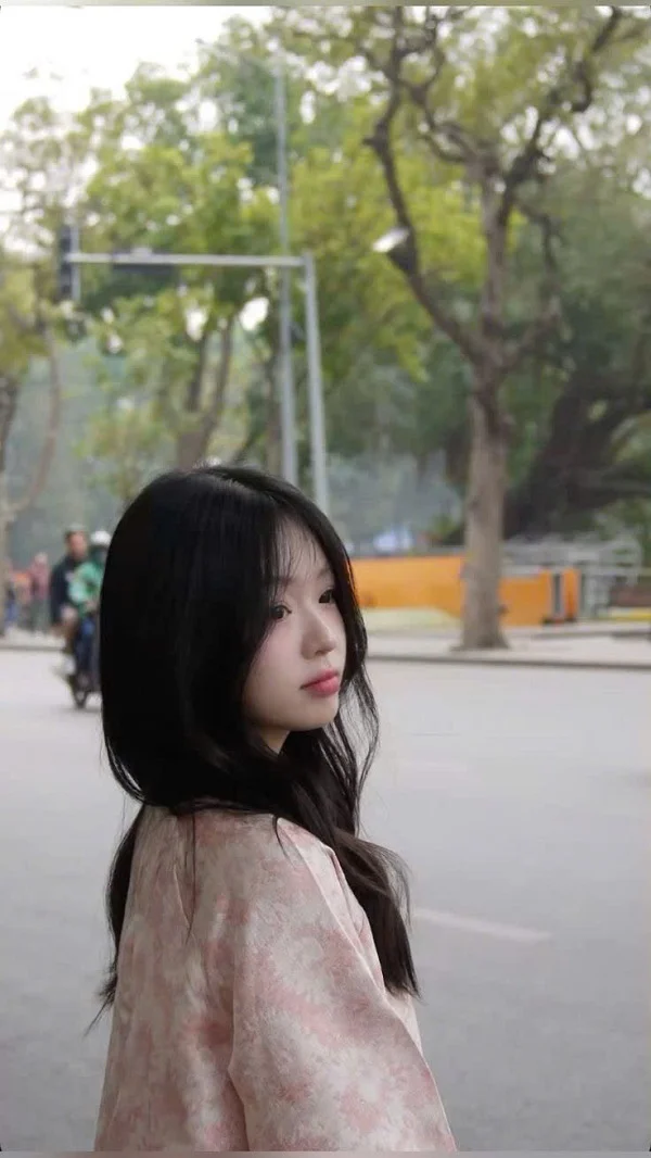 Một gái xinh cute với mái tóc đen dài đang đứng trên đường phố